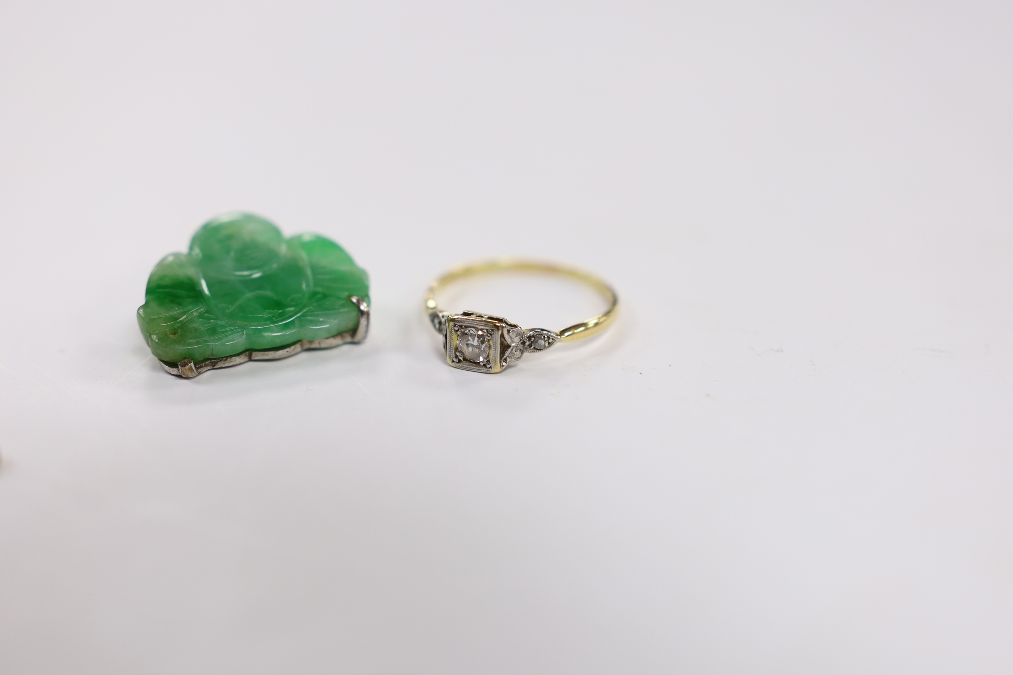 An Edwardian 9ct, aquamarine and seed pearl cluster set bar brooch, 54mm, a Chinese mounted jade Buddha pendant and an 18ct and single stone diamond set ring, with diamond chip set shoulders.